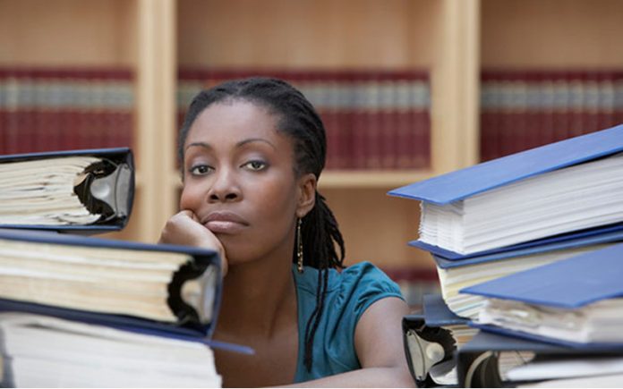 Office worker sitting behind stacks of documents in office, portrait